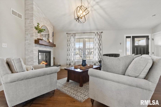 living room featuring lofted ceiling, dark hardwood / wood-style flooring, and a stone fireplace