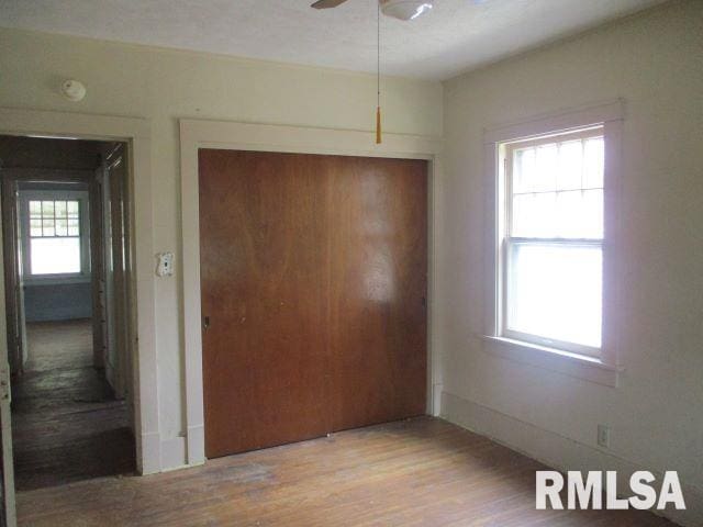 unfurnished bedroom featuring multiple windows, a closet, ceiling fan, and light wood-type flooring