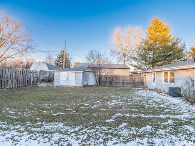 snowy yard with a storage shed and central AC