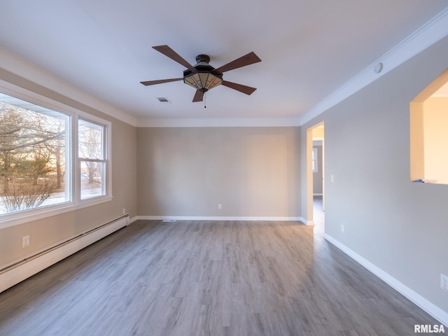 spare room featuring ceiling fan, baseboard heating, ornamental molding, and wood-type flooring