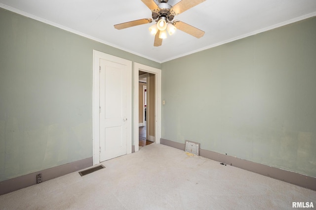 empty room featuring ceiling fan, light colored carpet, and ornamental molding