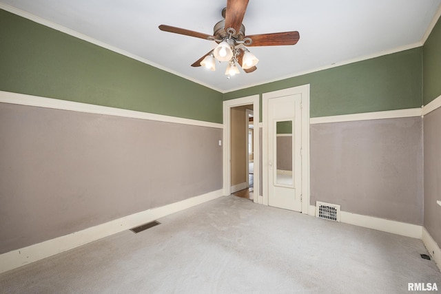 carpeted spare room with ceiling fan and ornamental molding