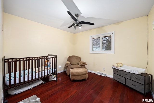 bedroom featuring ceiling fan, dark hardwood / wood-style floors, and a crib