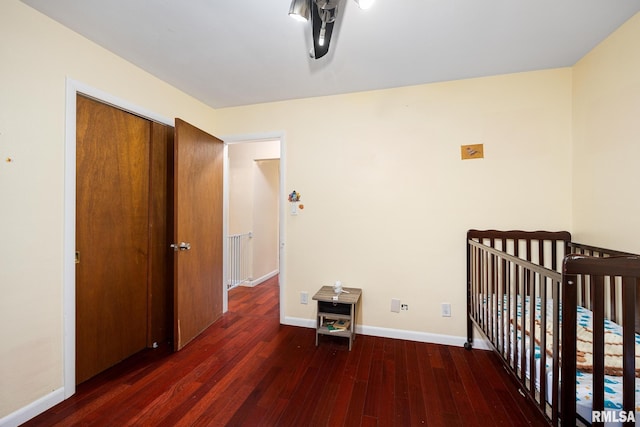 bedroom with a nursery area, a closet, and dark hardwood / wood-style flooring