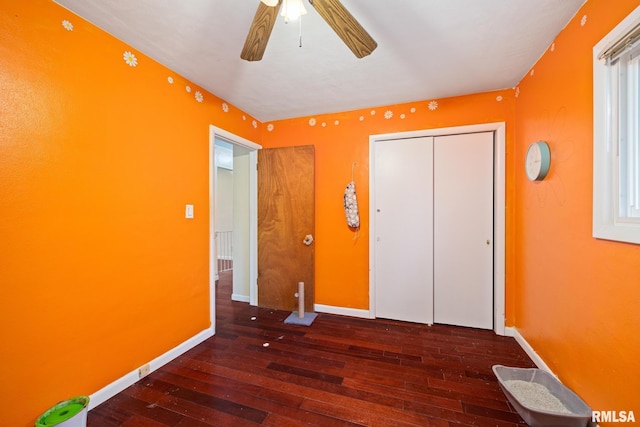 unfurnished bedroom with ceiling fan, dark hardwood / wood-style flooring, and a closet