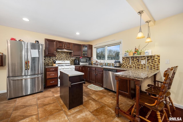 kitchen featuring appliances with stainless steel finishes, a kitchen island, tasteful backsplash, kitchen peninsula, and dark brown cabinets