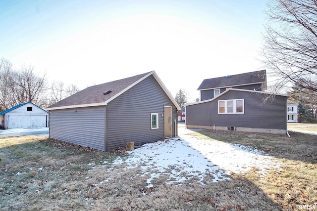 view of snowy exterior featuring a garage and an outdoor structure