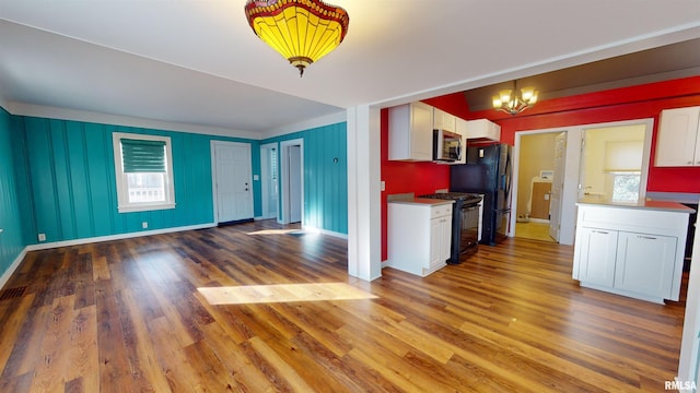 kitchen featuring a wealth of natural light, white cabinetry, hardwood / wood-style floors, and black appliances