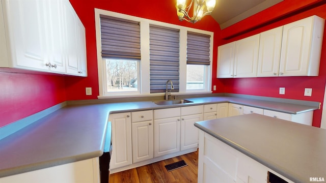 kitchen with dark hardwood / wood-style floors, a notable chandelier, lofted ceiling, white cabinets, and sink