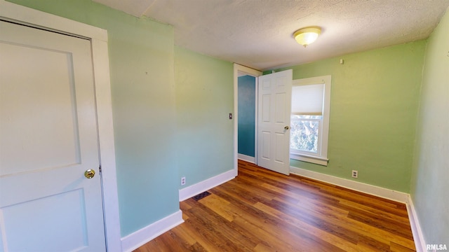 unfurnished bedroom with a closet, a textured ceiling, and hardwood / wood-style floors