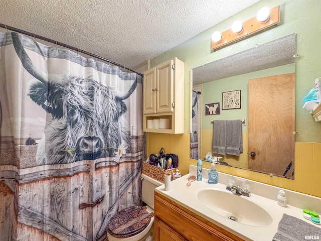 bathroom featuring toilet, vanity, walk in shower, and a textured ceiling