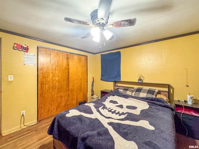 bedroom with ceiling fan, a closet, crown molding, and hardwood / wood-style flooring