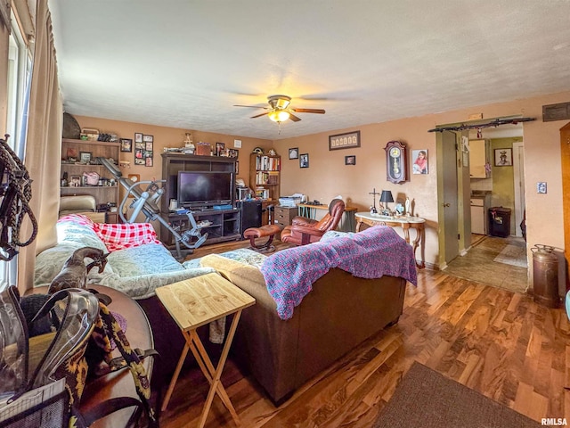 living room with a textured ceiling, ceiling fan, and hardwood / wood-style flooring