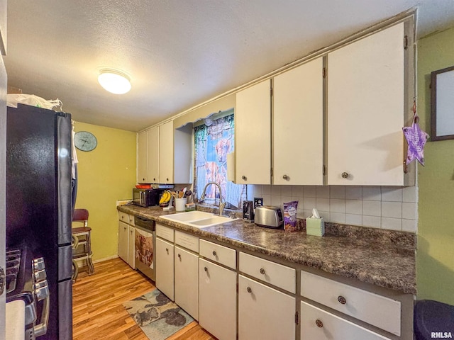 kitchen featuring backsplash, sink, white cabinetry, light hardwood / wood-style flooring, and appliances with stainless steel finishes