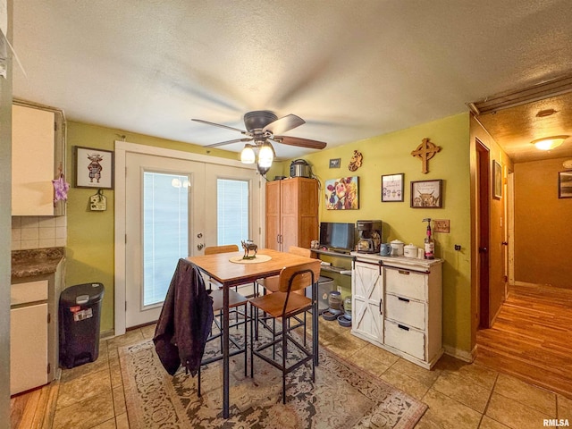 dining area with a textured ceiling, ceiling fan, and french doors