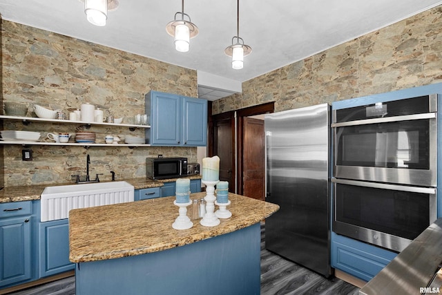 kitchen featuring blue cabinets, decorative light fixtures, wood walls, and sink