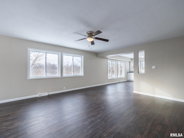 empty room featuring a healthy amount of sunlight, dark wood-type flooring, and ceiling fan