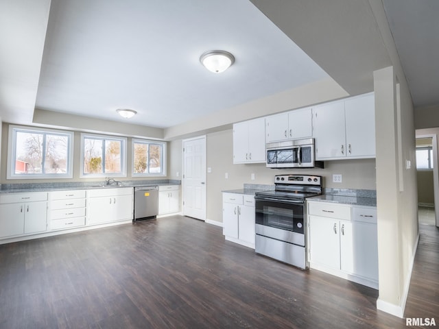 kitchen featuring white cabinets, sink, stainless steel appliances, light stone counters, and dark hardwood / wood-style floors