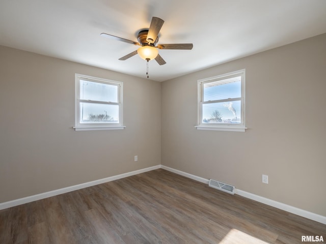 empty room with ceiling fan, dark wood-type flooring, and a wealth of natural light