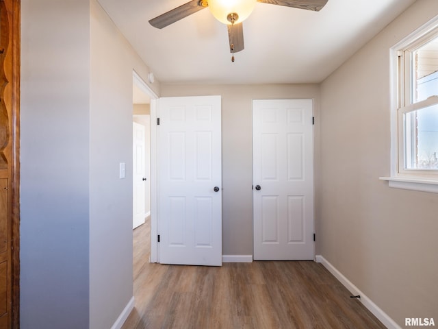 unfurnished bedroom with ceiling fan, hardwood / wood-style floors, and multiple windows