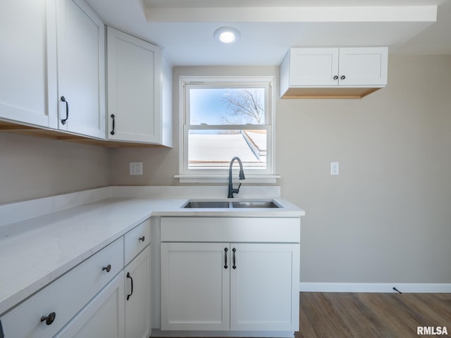 kitchen featuring sink, white cabinetry, dark hardwood / wood-style floors, and light stone counters