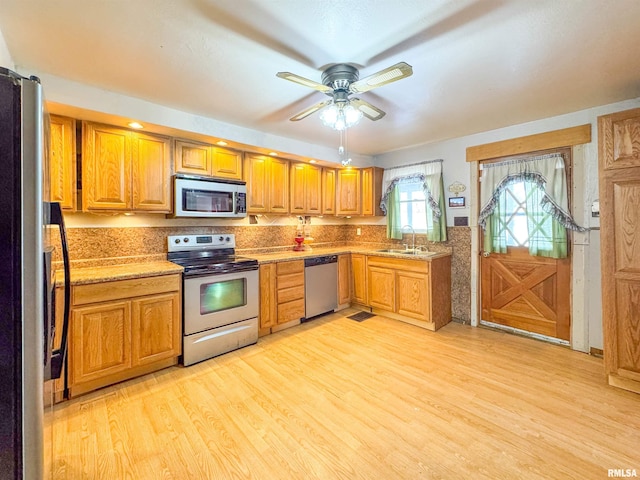 kitchen with sink, light wood-type flooring, ceiling fan, and appliances with stainless steel finishes