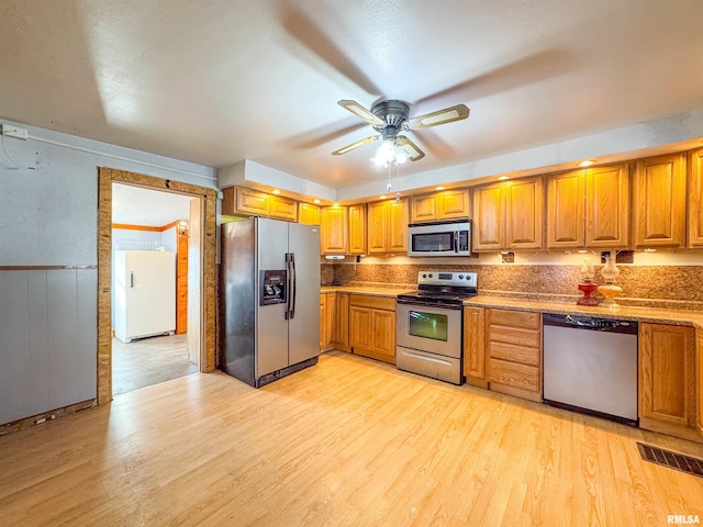 kitchen featuring ceiling fan, decorative backsplash, stainless steel appliances, and light hardwood / wood-style flooring