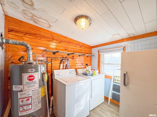 laundry room featuring wood ceiling, light hardwood / wood-style flooring, gas water heater, washer and dryer, and wood walls