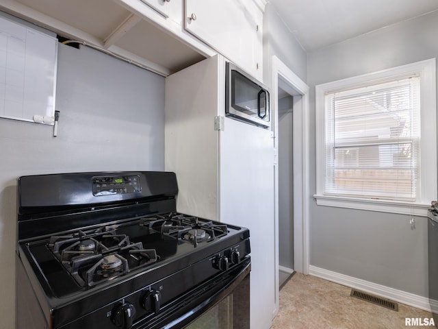 kitchen featuring white cabinets, stainless steel microwave, and black gas range oven