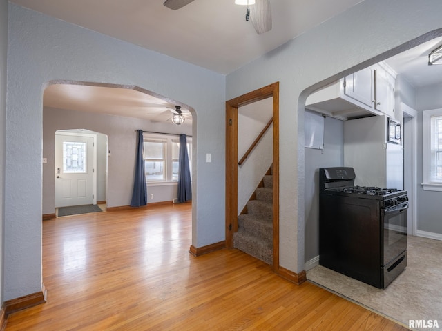 kitchen with ceiling fan, white cabinetry, light hardwood / wood-style flooring, and gas stove