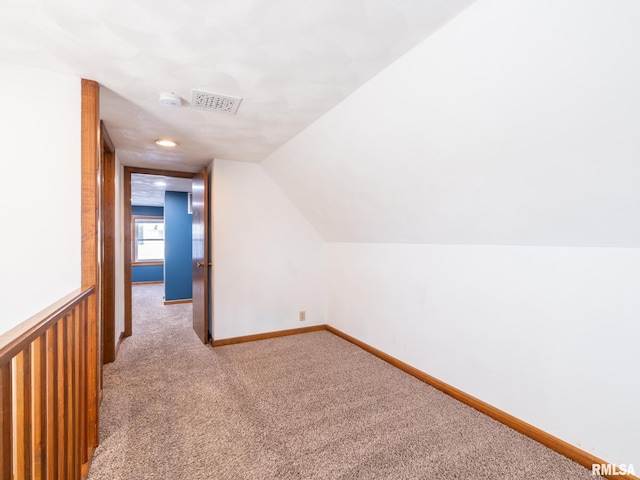 additional living space featuring light carpet and vaulted ceiling