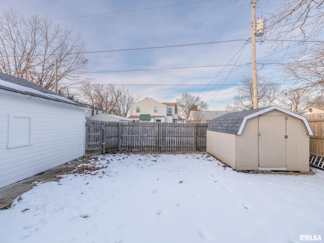 snowy yard featuring a storage unit