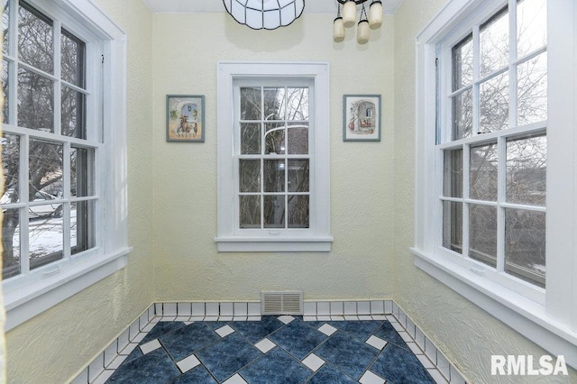 unfurnished sunroom featuring a wealth of natural light and a notable chandelier