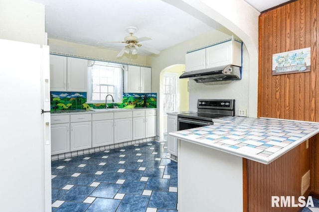 kitchen with kitchen peninsula, sink, white cabinetry, stainless steel range with electric stovetop, and tile countertops