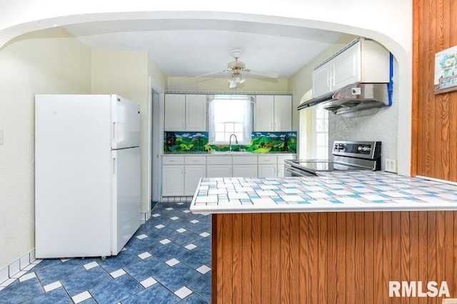 kitchen with white cabinetry, kitchen peninsula, stainless steel electric range, and white fridge