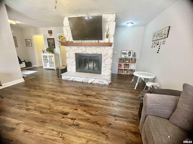 living room with dark hardwood / wood-style flooring and a stone fireplace