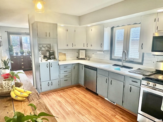 kitchen with sink, stainless steel appliances, decorative backsplash, and gray cabinets