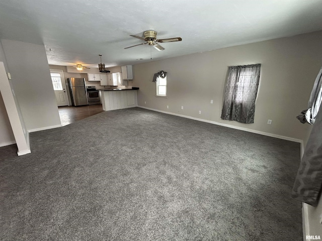 unfurnished living room with ceiling fan, dark carpet, and a textured ceiling