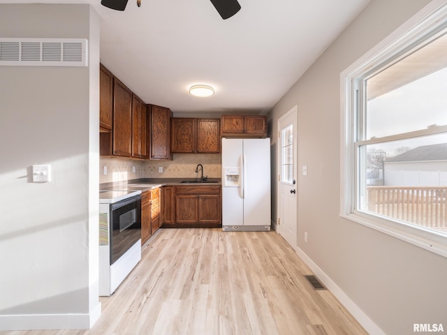 kitchen with white appliances, light hardwood / wood-style floors, tasteful backsplash, sink, and ceiling fan