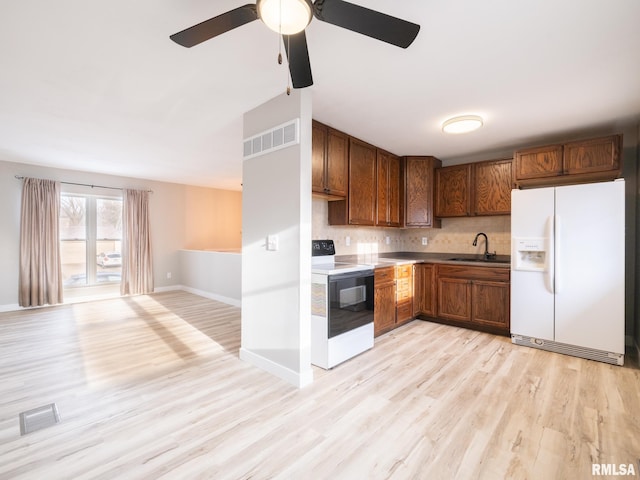 kitchen with sink, white appliances, light hardwood / wood-style floors, and decorative backsplash