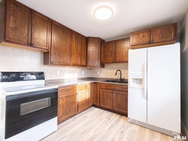 kitchen with light hardwood / wood-style flooring, range with electric stovetop, white refrigerator with ice dispenser, sink, and decorative backsplash