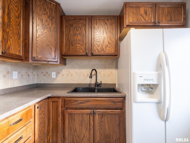 kitchen with sink, white fridge with ice dispenser, and backsplash