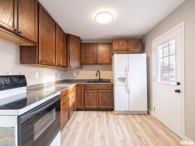 kitchen with light hardwood / wood-style flooring, white refrigerator with ice dispenser, sink, backsplash, and range with electric cooktop