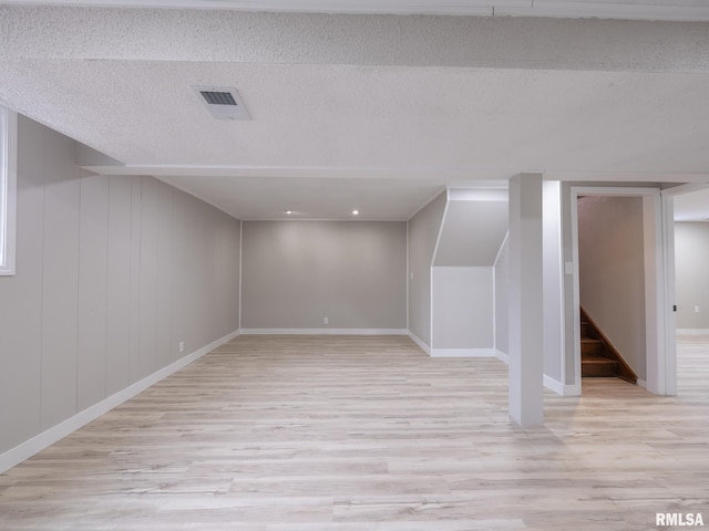 additional living space with light wood-type flooring and a textured ceiling