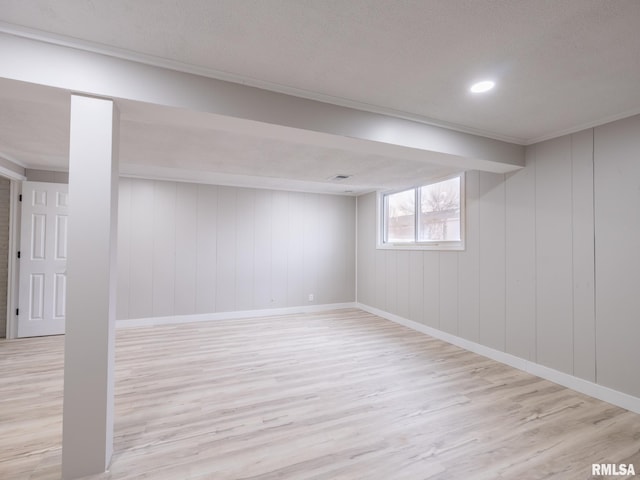 basement with light hardwood / wood-style flooring and wooden walls