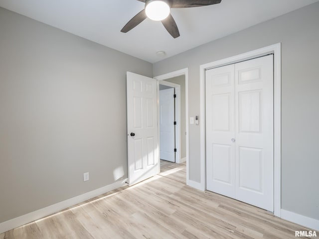 unfurnished bedroom featuring ceiling fan, a closet, and light wood-type flooring