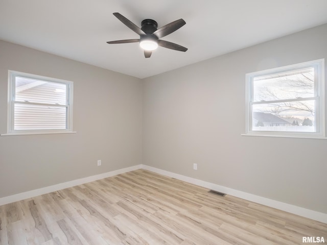 empty room featuring ceiling fan, light wood-type flooring, and a healthy amount of sunlight