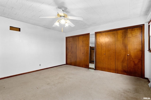 unfurnished bedroom with multiple closets, ceiling fan, and light carpet