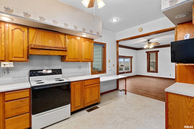 kitchen featuring premium range hood, crown molding, range with electric cooktop, ceiling fan, and decorative backsplash