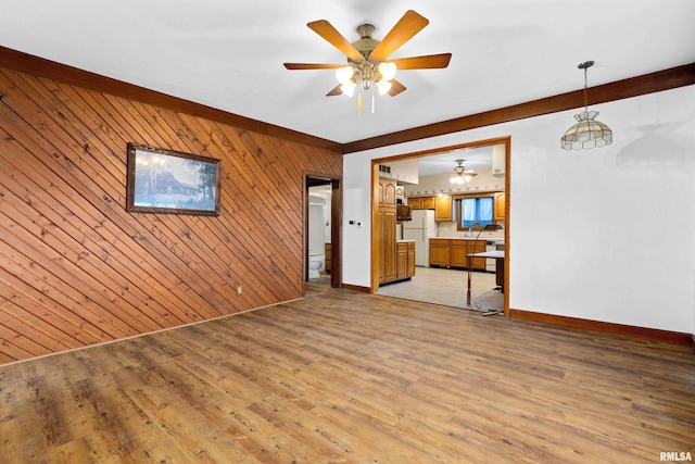 spare room featuring ceiling fan, wooden walls, and light hardwood / wood-style flooring